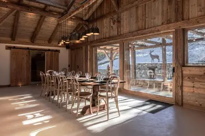 a dining room with a table and chairs and windows at Ferme des Choseaux - Grand Confort et ski in Combloux