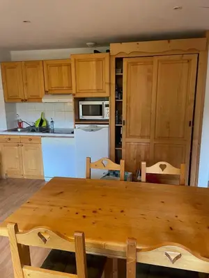 a kitchen with a wooden table with chairs and a kitchen with at Appartement 4 personnes in Combloux