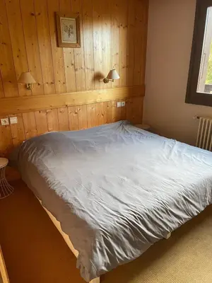a bed in a bedroom with wood paneling at Appartement 4 personnes in Combloux