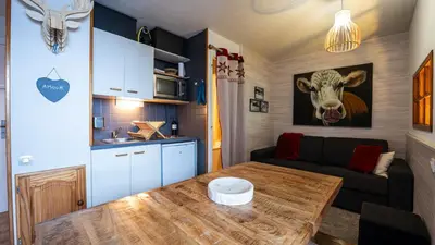 a living room with a table and a cow on the wall at Grande Neige N 33 - 2P5 in Morillon