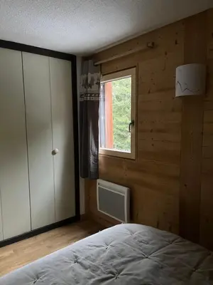 a bedroom with a bed and a window at Carroz d Araches , 2 pièces rénové vue montagne, 4 personnes, 3 min du centre, parking,balcon in Arâches-la-Frasse