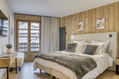 a bedroom with a large bed and a window at Écrin de raffinement au cœur de Megève in Megève