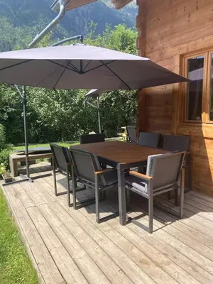 a wooden table with chairs and an umbrella on a deck at Chamlomy in Chamonix-Mont-Blanc