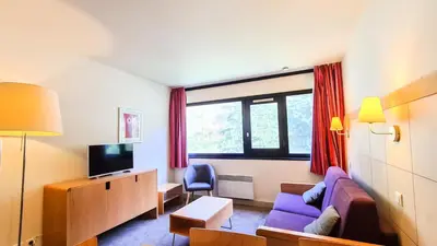 a living room with a purple couch and a tv at Residence De La Foret - Appartement confortable · Au pied des pistes MAE-9991 in Magland
