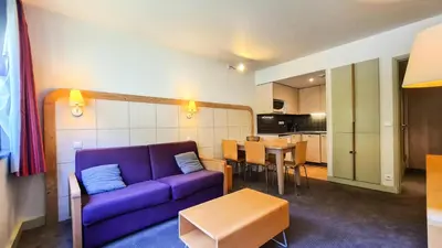 a living room with a purple couch and a kitchen at Residence De La Foret - Appartement confortable · Au pied des pistes MAE-9991 in Magland