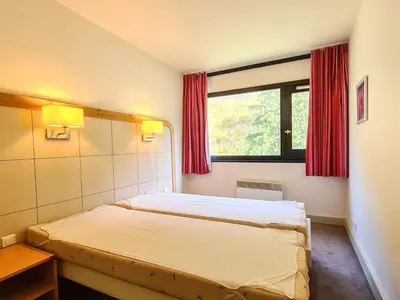 a bedroom with a bed and a window with red curtains at 2 Pièces Confort au Pied des Pistes, Flaine - FR-1-425-228 in Arâches-la-Frasse