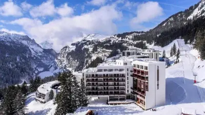 a hotel in the snow with mountains in the background at Résidence Le Panoramic - Appartement lumineux · Départ et retour skis aux pieds · Piscine · Parking inclus · Spa · wifi MAE-0351 in Magland