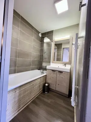 a bathroom with a tub and a sink and a mirror at Résidence Le Panoramic - Appartement lumineux · Départ et retour skis aux pieds · Piscine · Parking inclus · Spa · wifi MAE-0351 in Magland