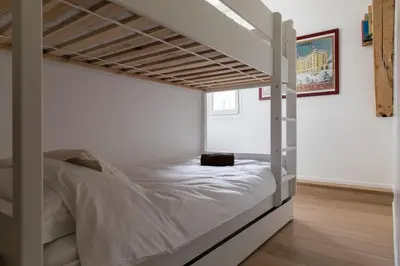 a bedroom with a bunk bed with white sheets at Le Majestic 145 Apartment - Chamonix All Year in Chamonix-Mont-Blanc