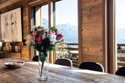 a vase of flowers sitting on a wooden table at Chalet Combloran in Combloux