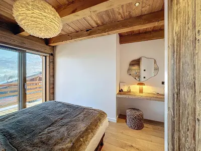 a bedroom with a large bed and a large window at Chalet Combloran in Combloux