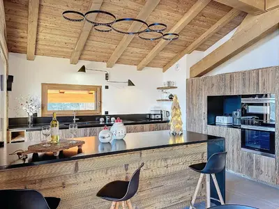 a kitchen with a counter with chairs and a table at Chalet Combloran in Combloux