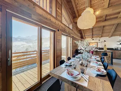 a dining room with a long table and a large window at Chalet Combloran in Combloux