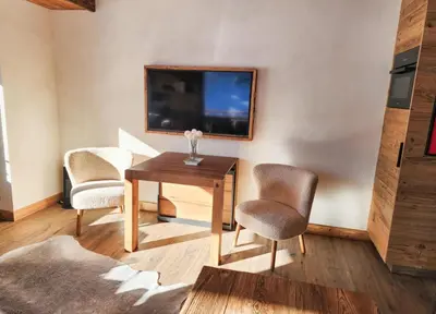 a living room with a table and chairs and a tv at Reflets de Megève in Megève