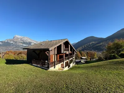 a small house in a field with mountains in the background at Appartement Proche Des Pistes in Saint-Gervais-les-Bains