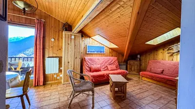 a living room with a red couch and a table at Appartement Proche Des Pistes in Saint-Gervais-les-Bains