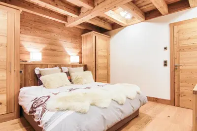 a bedroom with a large bed with wooden walls at Chalet La Petite Forêt in Megève