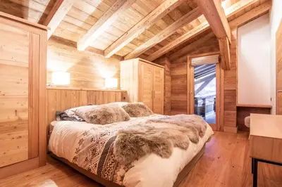 a bedroom with a bed in a room with wooden walls at Chalet La Petite Forêt in Megève