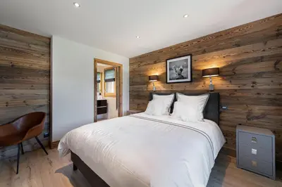 a bedroom with a white bed and wooden walls at Chalet Le Chardon Bleu in Megève