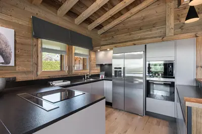 a kitchen with stainless steel appliances and wooden ceilings at Chalet Le Chardon Bleu in Megève