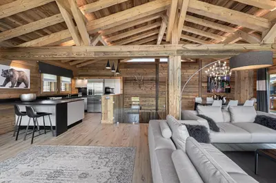 an open living room and kitchen with wooden ceilings at Chalet Le Chardon Bleu in Megève