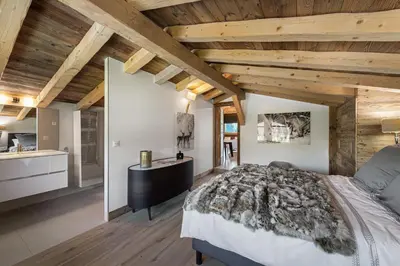 a bedroom with a large bed and wooden ceilings at Chalet Le Chardon Bleu in Megève