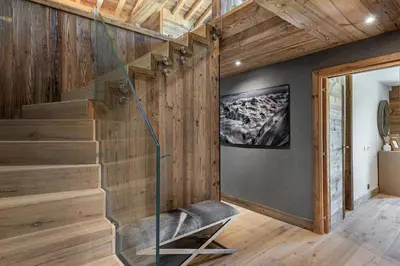 a glass staircase in a room with wooden walls at Chalet Le Chardon Bleu in Megève