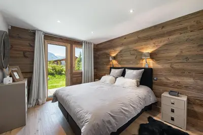 a bedroom with wooden walls and a bed with pillows at Chalet Le Chardon Bleu in Megève