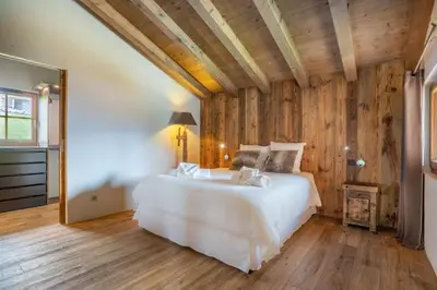 a bedroom with a white bed and wooden walls at Chalet Les Marmottes in Combloux