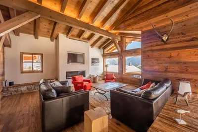 a living room with leather furniture and wooden ceilings at Chalet Les Marmottes in Combloux