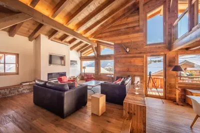 a living room with leather furniture and wooden ceilings at Chalet Les Marmottes in Combloux