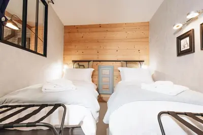 two beds in a room with wooden walls at Design flat-center of Samoëns in Samoëns