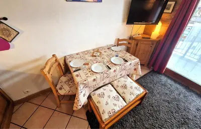 a table and chairs with a table and a television at La Ginabelle 2 - Vue MontBlanc in Chamonix-Mont-Blanc