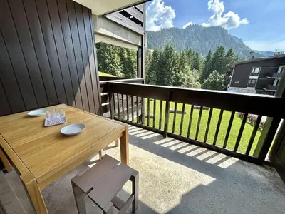 a wooden table and chairs on a balcony with a view at Studio à Megève avec parking souterrain et casier à skis - FR-1-597-189 in Megève