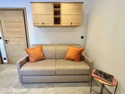 a couch with orange pillows in a living room at Studio confortable proche du centre avec parking, navette et randonnées à Megève - FR-1-597-190 in Megève