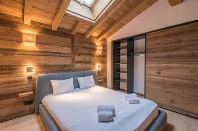 a bedroom with a bed in a room with wooden walls at Duplex des Rois - Welkeys in Megève
