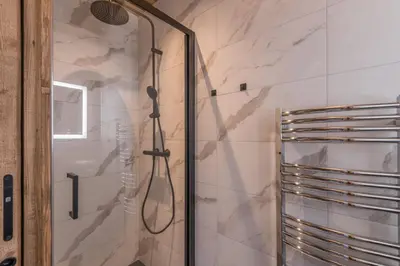 a shower with a glass door in a bathroom at Duplex des Rois - Welkeys in Megève