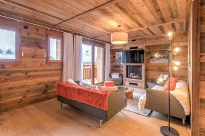 a living room with wooden walls and a couch and a bed at Duplex des Rois - Welkeys in Megève