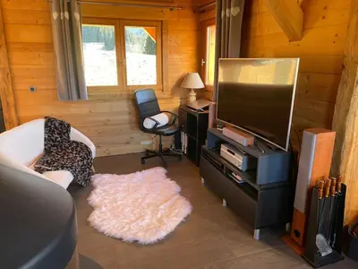 a living room with a flat screen tv and a rug at Chalet La Pioleute Megève in Megève