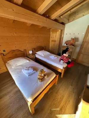 two beds in a wooden room with a child sitting on the floor at Chalet La Pioleute Megève in Megève