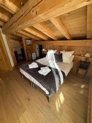 a bedroom with a bed in a wooden attic at Chalet La Pioleute Megève in Megève
