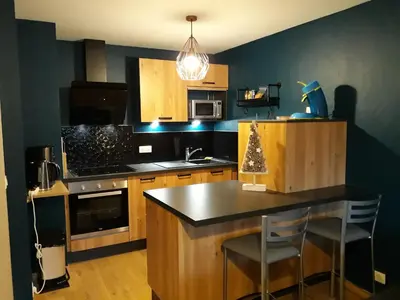 a kitchen with a black counter top and wooden cabinets at Le Haut du Rosay in Sallanches