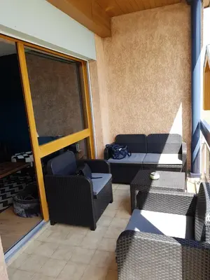 an outdoor patio with wicker chairs and a table at Le Haut du Rosay in Sallanches
