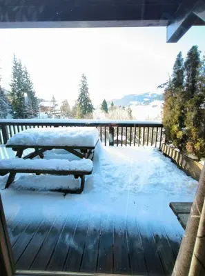 a wooden deck with a bench covered in snow at Apartment in residence near the Mont d'Arbois in Megève