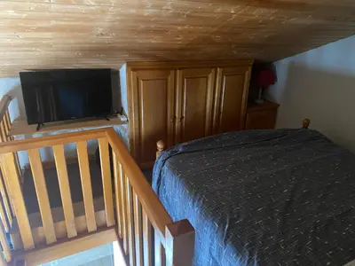a bedroom with a bed and a staircase with a television at Les blanches aiguilles in Les Carroz d'Araches