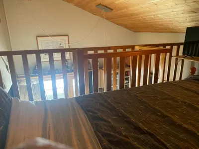 a bedroom with a bed and a wooden railing at Les blanches aiguilles in Les Carroz d'Araches