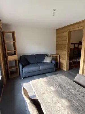 a living room with a blue couch and a table at Le Nid Douillet des Gerets in Saint-Gervais-les-Bains