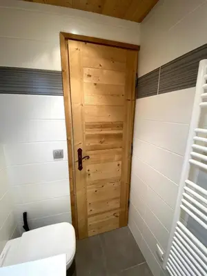 a bathroom with a toilet and a wooden door at Le Nid Douillet des Gerets in Saint-Gervais-les-Bains