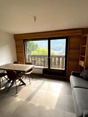 a living room with a table and a large window at Le Nid Douillet des Gerets in Saint-Gervais-les-Bains