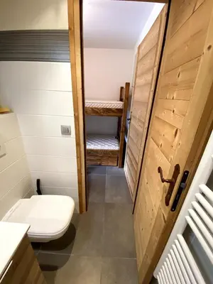 a small bathroom with a toilet and a wooden door at Le Nid Douillet des Gerets in Saint-Gervais-les-Bains